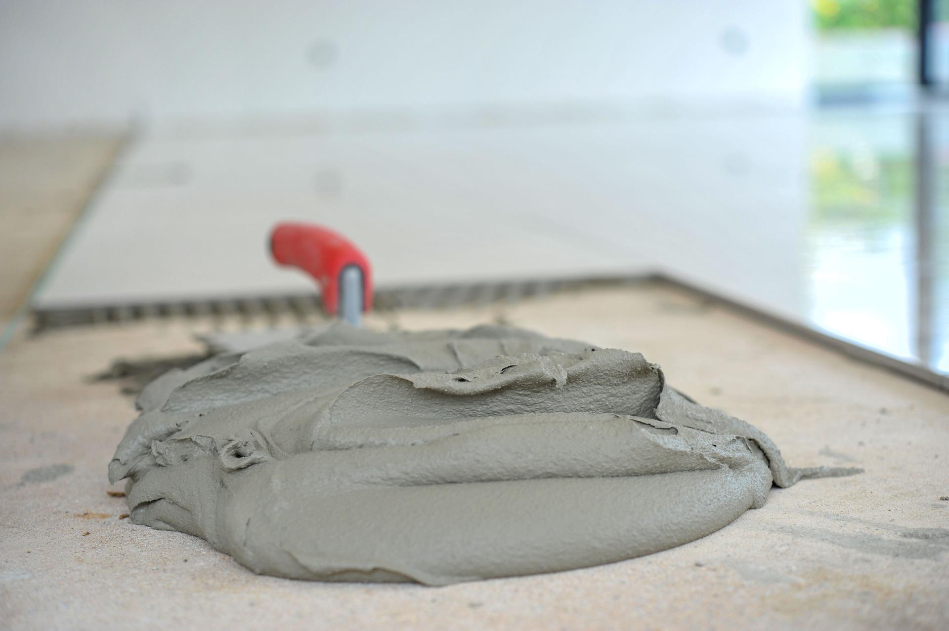 Grande mucchio di adesivo per piastrelle con una cazzuola in un nuovo appartamento