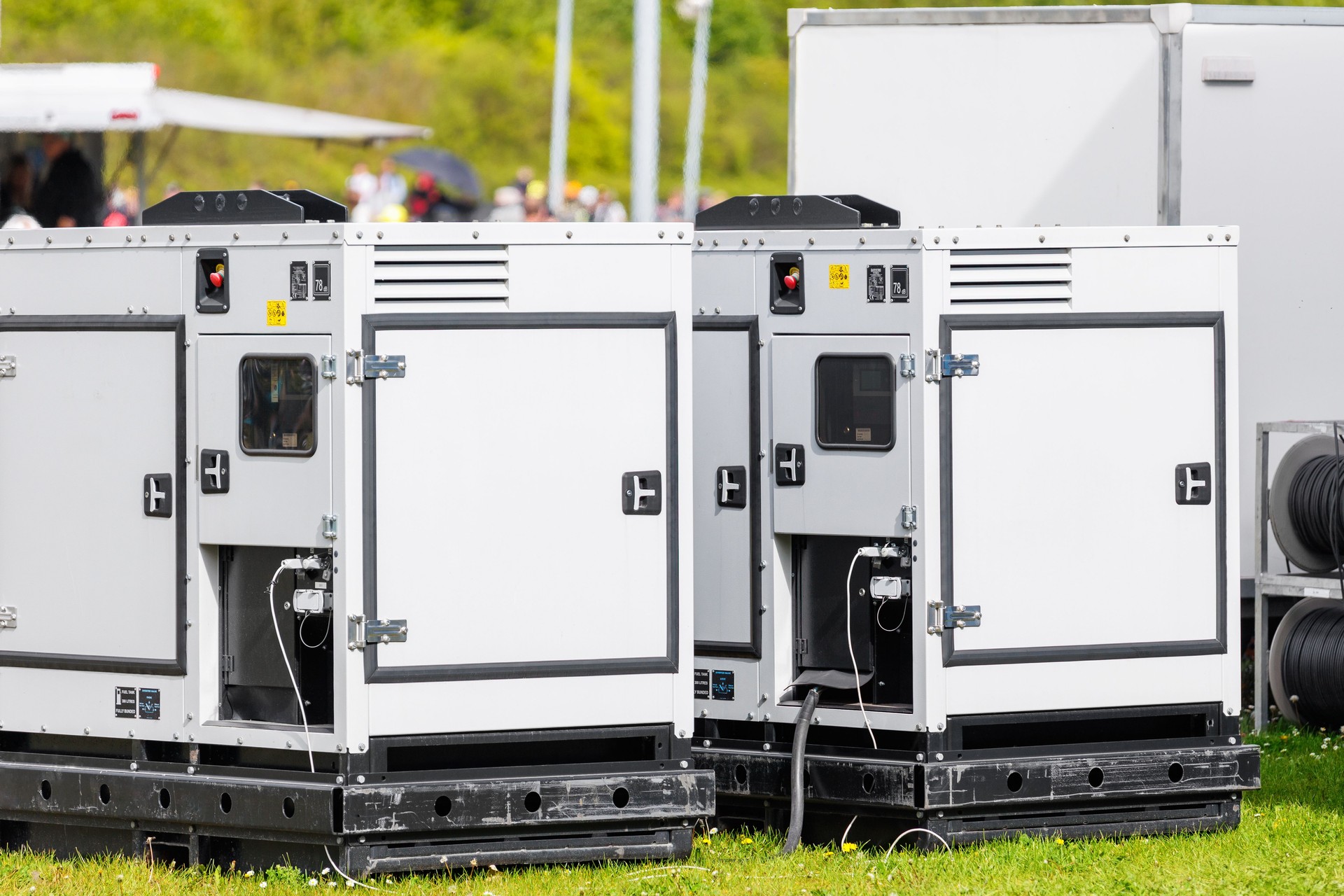 Imposta due grandi generatori di carburante industriali portatili prato verde in occasione di un evento commerciale all'aperto sfondo cielo azzurro chiaro. Fornitura elettrica mobile, impianto di energia, unità di backup, servizio di noleggio attrezzature